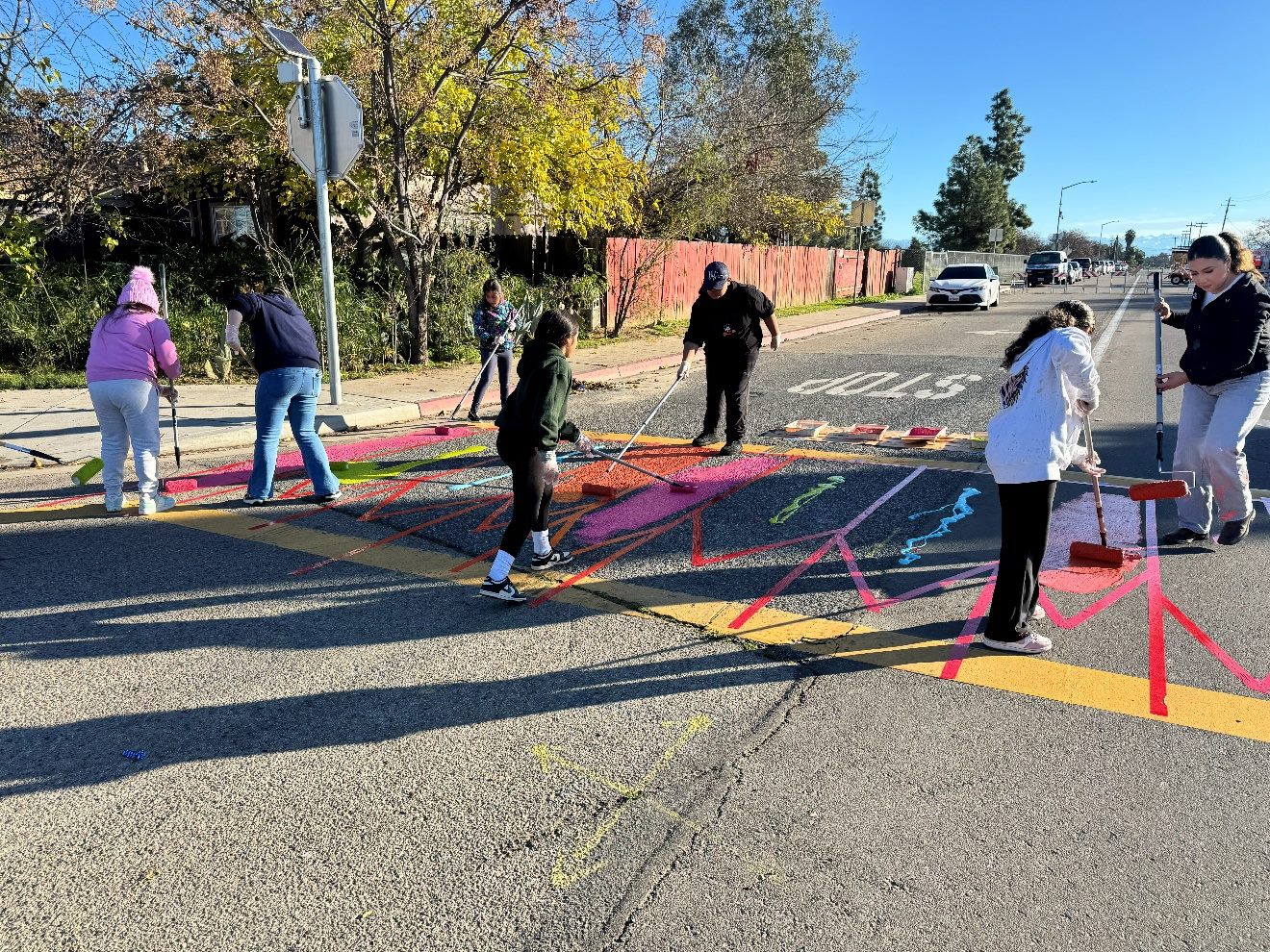 Community members painting a colorful crosswalk together in the street